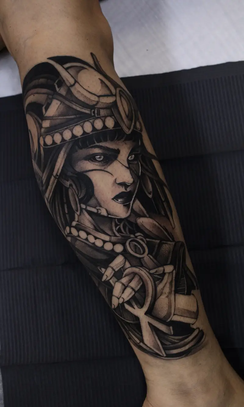 Deusa Ísis com cocar, colar de contas e ankh, tatuada na perna